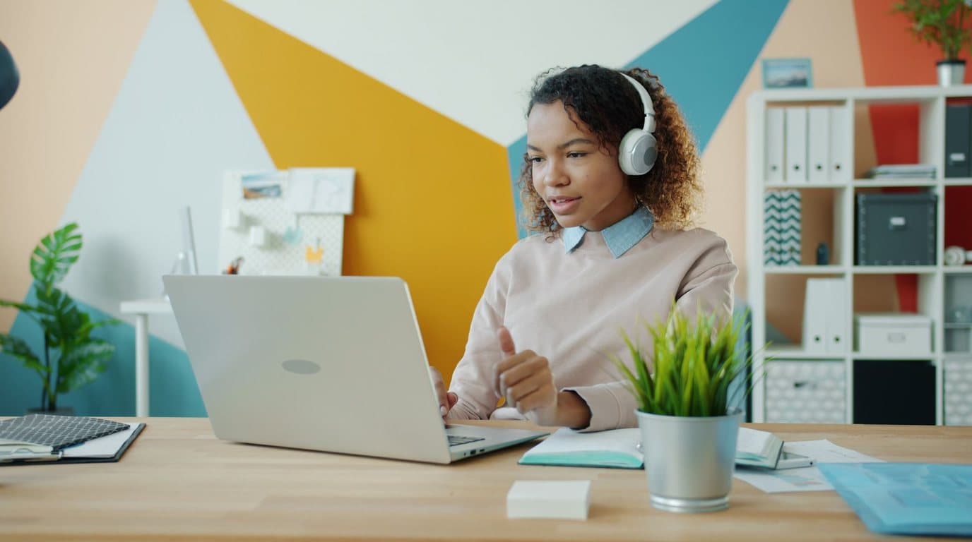 A woman wearing headphones taking part in an online lesson on her laptop